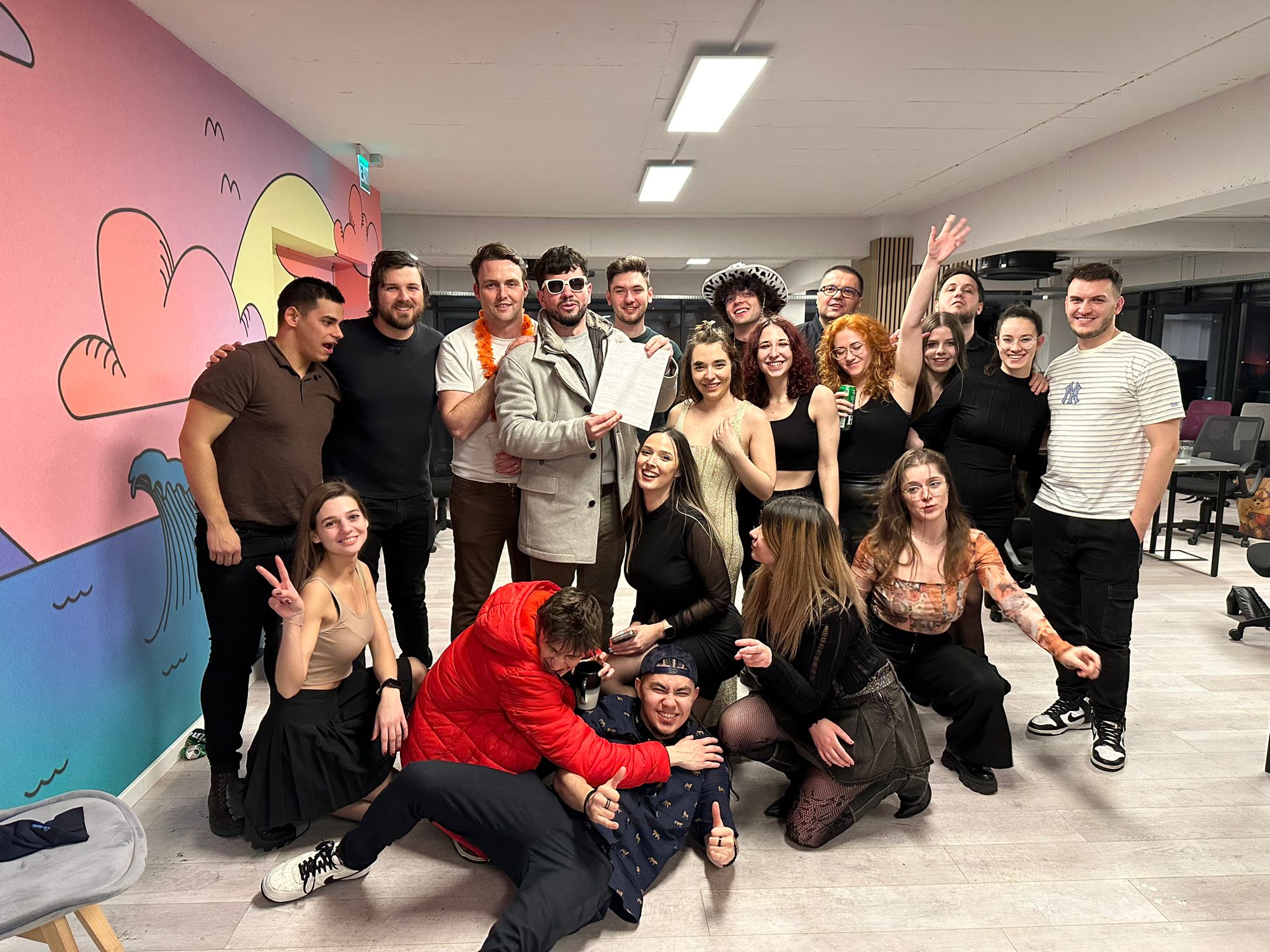 Full team photo at Halloween party with colorful mural and costumes