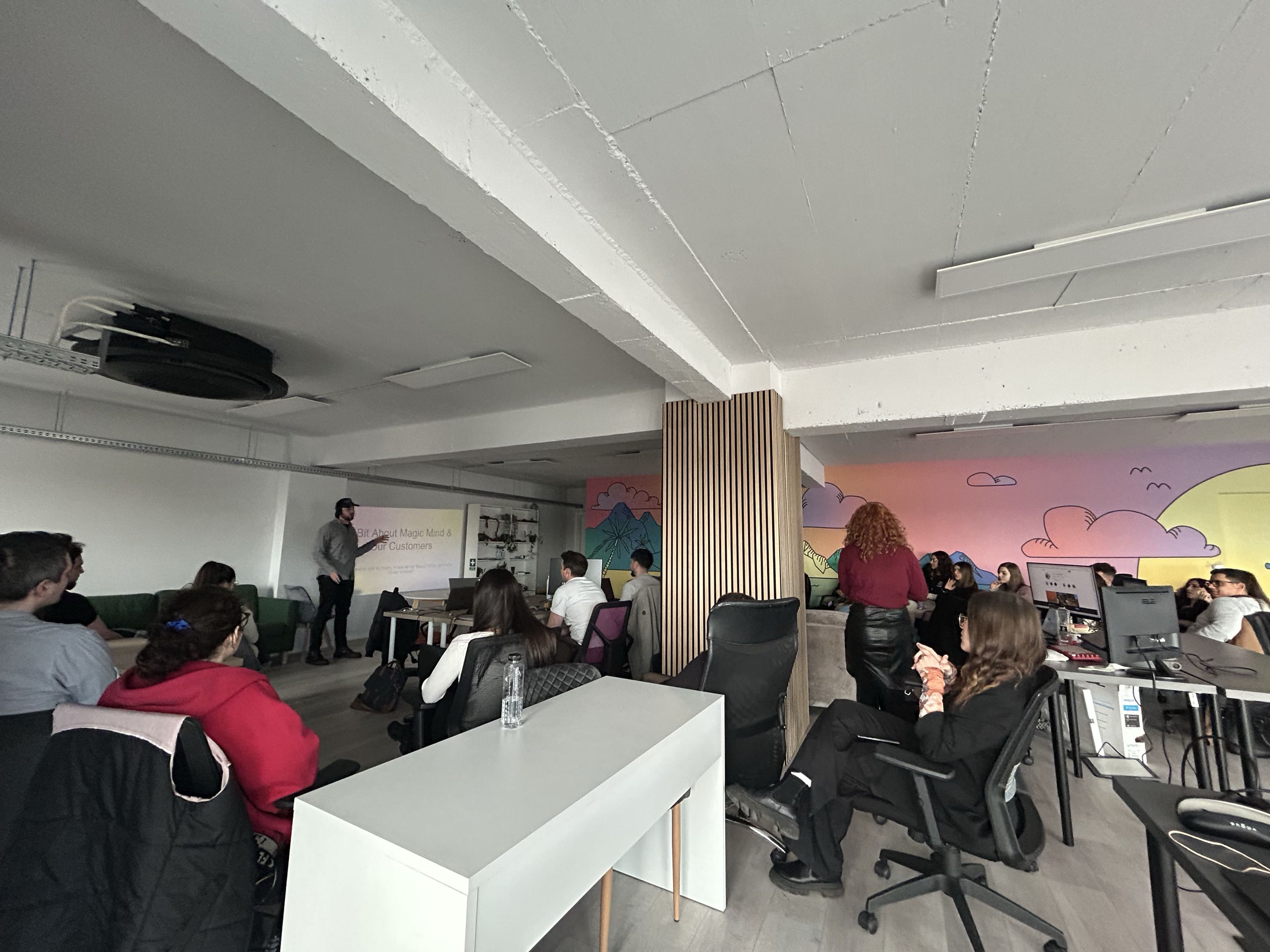 Sebastian presenting to team with projector, colorful mural backdrop